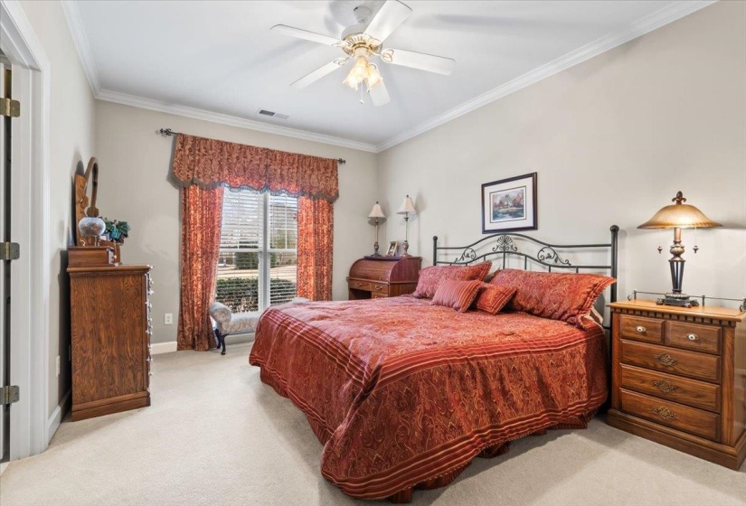 Bedroom featuring ceiling fan, light colored carpet, and ornamental molding