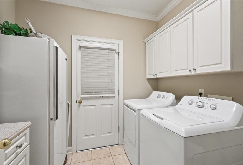 Clothes washing area featuring cabinets, washer and clothes dryer, crown molding, and light tile patterned flooring