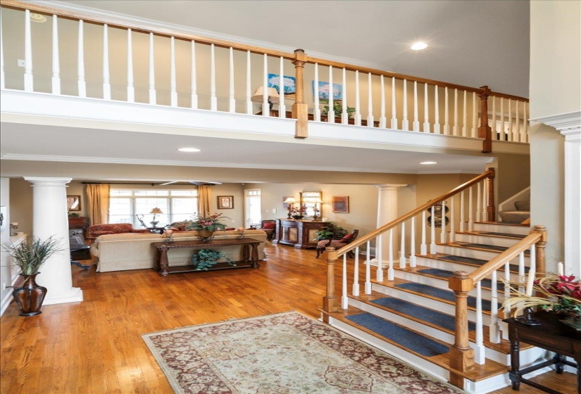 Staircase with crown molding, hardwood / wood-style flooring, and decorative columns