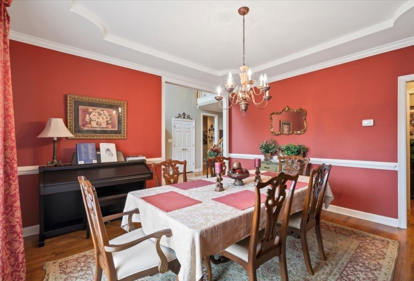 Dining area with crown molding, an inviting chandelier, a tray ceiling, and hardwood / wood-style floors