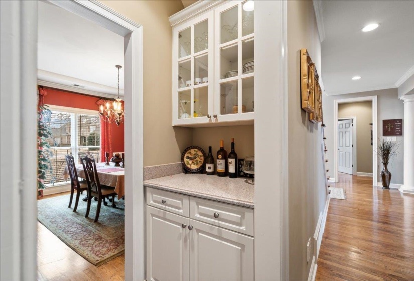 Bar with white cabinetry, light hardwood / wood-style flooring, crown molding, and an inviting chandelier