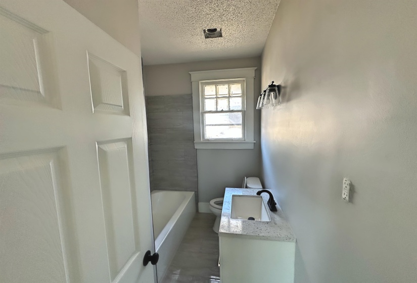 Bathroom featuring a textured ceiling, toilet, and vanity