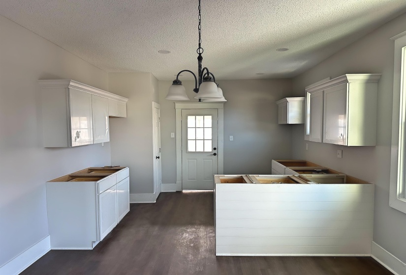 Kitchen featuring decorative light fixtures, dark wood-type flooring, a textured ceiling, and an inviting chandelier