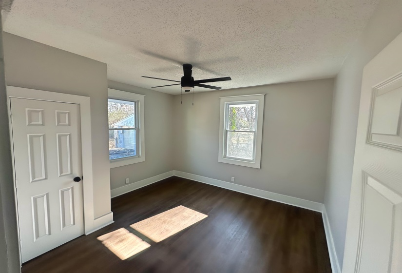 Unfurnished bedroom featuring ceiling fan, dark hardwood / wood-style flooring, and a textured ceiling