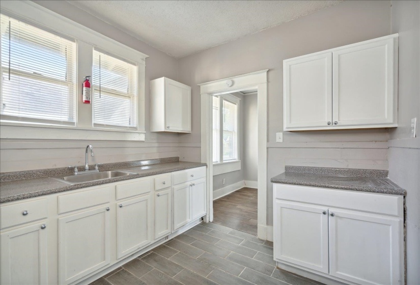 Kitchen with sink, a textured ceiling, white cabinets, and plenty of natural light