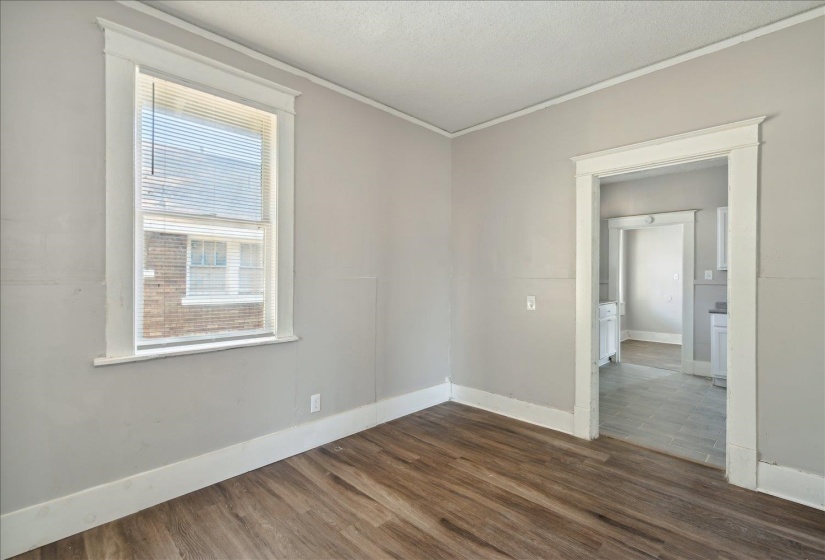 Empty room featuring dark wood-type flooring and crown molding