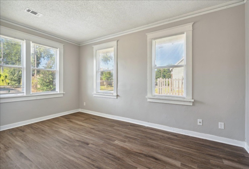 Unfurnished room with a textured ceiling, dark wood-type flooring, and crown molding