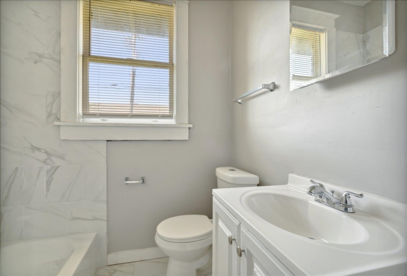 Bathroom with toilet, vanity, and plenty of natural light