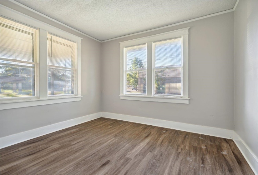 Empty room featuring a textured ceiling, dark hardwood / wood-style flooring, and ornamental molding