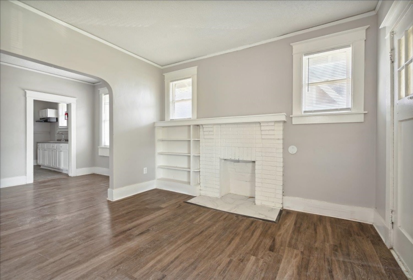 Unfurnished living room with a brick fireplace, sink, dark hardwood / wood-style floors, and ornamental molding