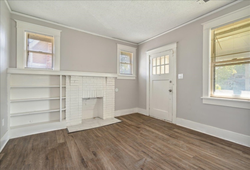 Unfurnished living room with a textured ceiling, a healthy amount of sunlight, and dark hardwood / wood-style floors