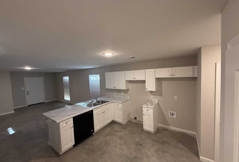 Kitchen with white cabinetry, black dishwasher, sink, and light stone counters