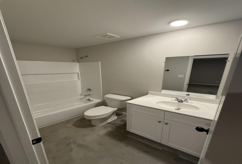 Full bathroom featuring concrete flooring, vanity, bathtub / shower combination, and toilet