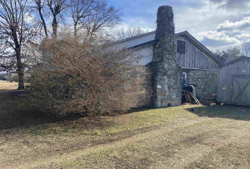 View of side of home featuring a yard and an outbuilding