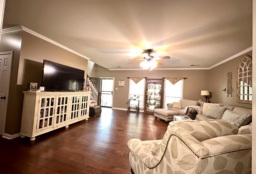 Living room featuring hardwood / wood-style floors, ceiling fan, plenty of natural light, baseboards, and crown molding