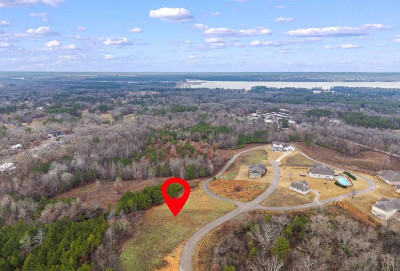 Aerial view of property and surrounding area featuring a large body of water and a heavily wooded area