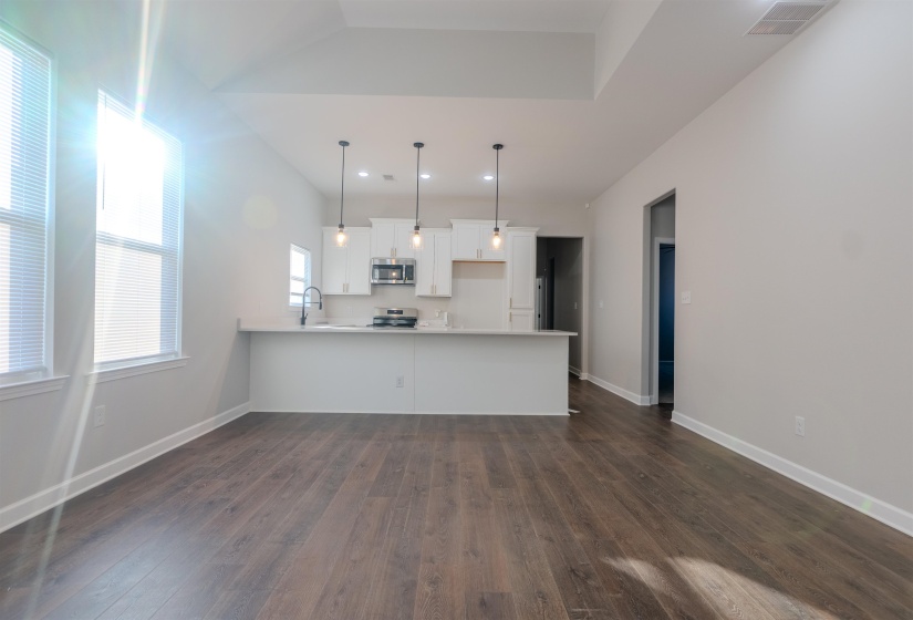 Kitchen featuring hanging light fixtures, stainless steel appliances, white cabinets, dark hardwood / wood-style floors, and kitchen peninsula