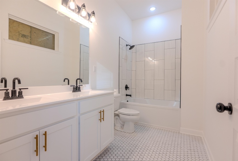 Full bathroom featuring toilet, vanity, tile patterned flooring, and tiled shower / bath combo