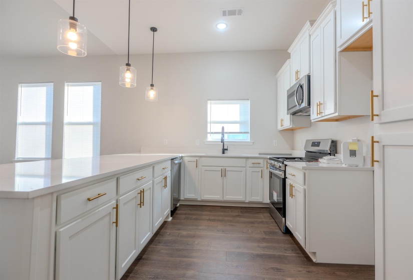 Kitchen with white cabinets, appliances with stainless steel finishes, pendant lighting, and kitchen peninsula