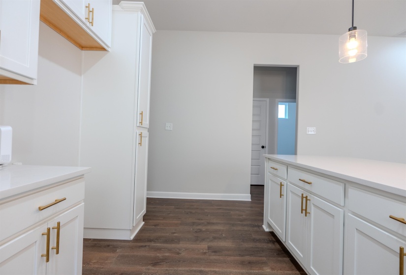 Kitchen with dark wood-type flooring, hanging light fixtures, and white cabinets