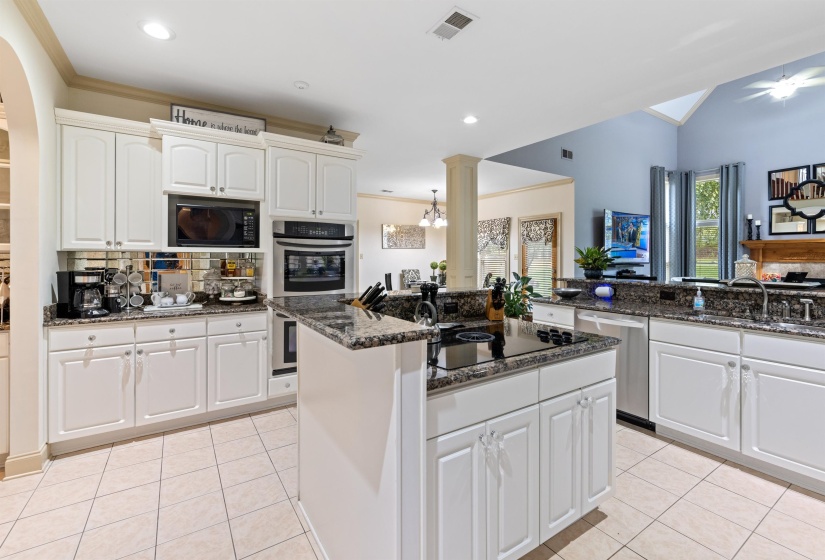 Kitchen with dark stone countertops, white cabinets, light tile patterned floors, and black appliances