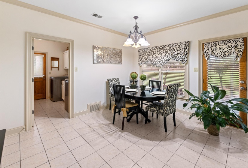 Tiled dining space featuring a notable chandelier, crown molding, and washing machine and clothes dryer