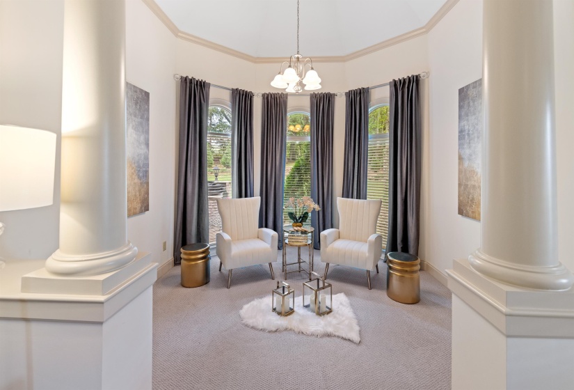 Living area featuring carpet floors, a healthy amount of sunlight, decorative columns, and a notable chandelier