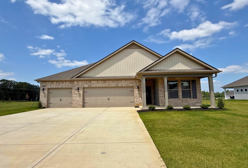 View of front of property featuring brick siding, a front yard, an attached garage, and driveway