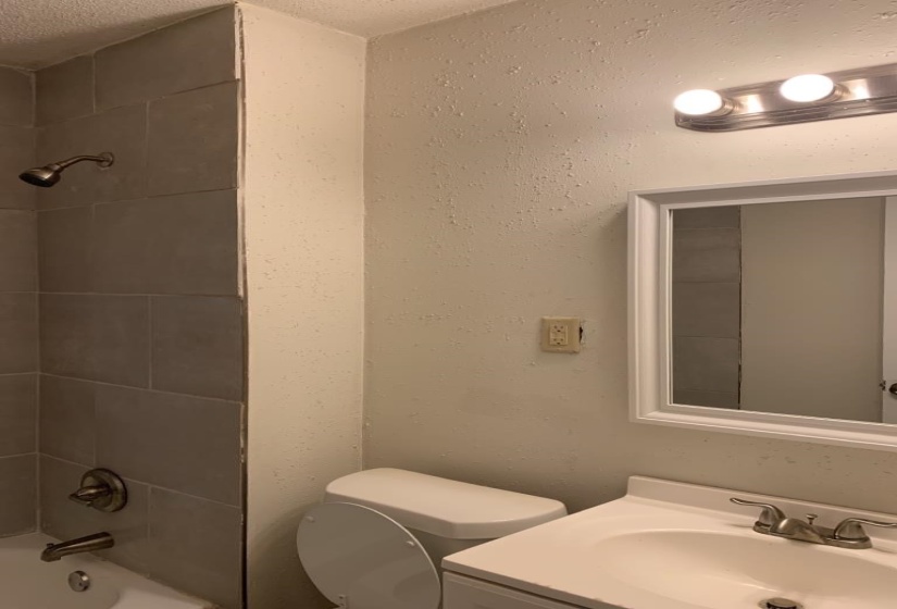 Full bathroom with vanity, a textured ceiling, toilet, and tiled shower / bath