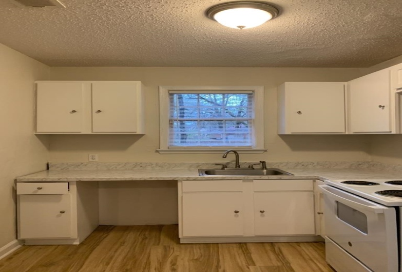 Kitchen featuring white range with electric stovetop, sink, light wood-type flooring, white cabinets, and a textured ceiling