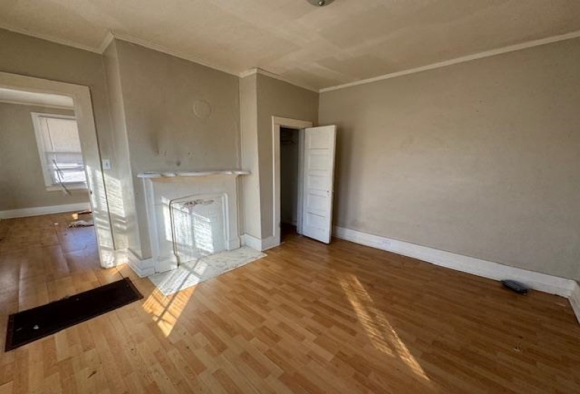 Unfurnished living room featuring wood-type flooring and ornamental molding