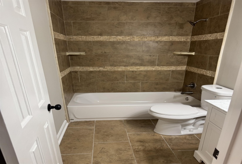 Full bathroom featuring vanity, tiled shower / bath combo, and toilet