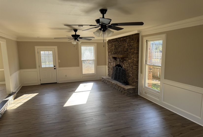 Unfurnished living room featuring ceiling fan, crown molding, and dark hardwood / wood-style floors