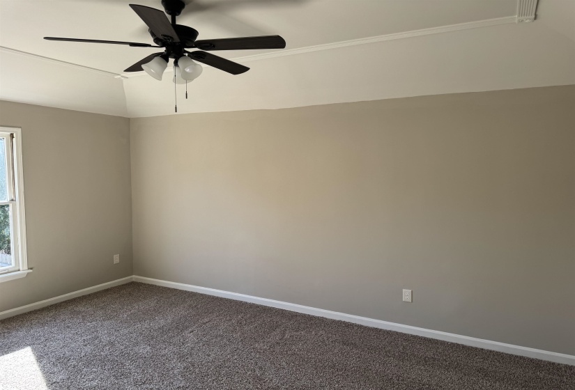 Empty room featuring carpet flooring, ceiling fan, and vaulted ceiling