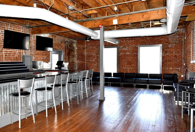 Interior space featuring brick wall and dark hardwood / wood-style flooring