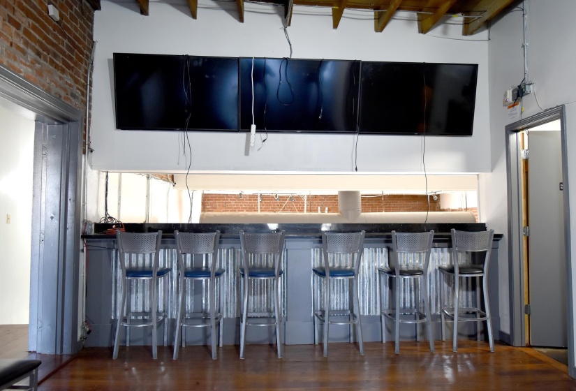 Overlook to downstairs; brick wall, dark hardwood / wood-style floors, and a towering ceiling