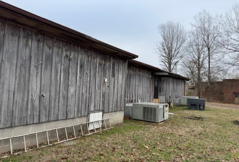 View of side of home with central AC unit and a lawn