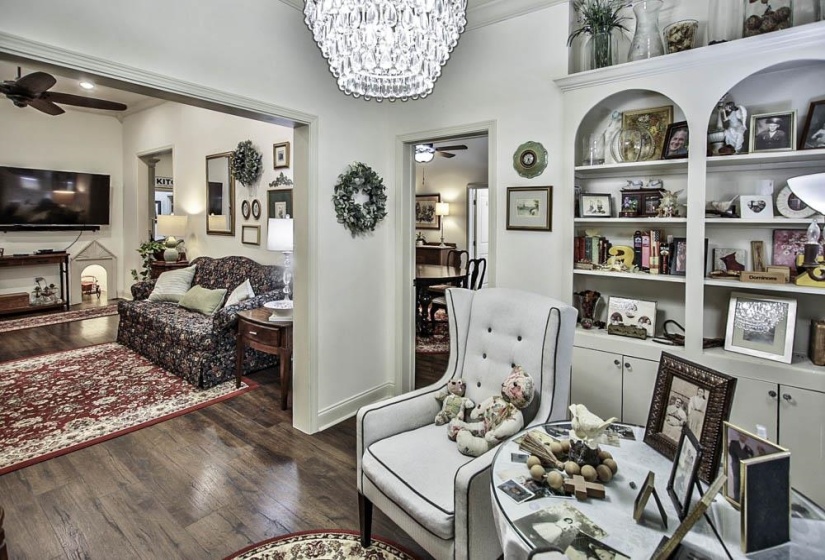 Living area with dark wood-type flooring and ceiling fan with notable chandelier