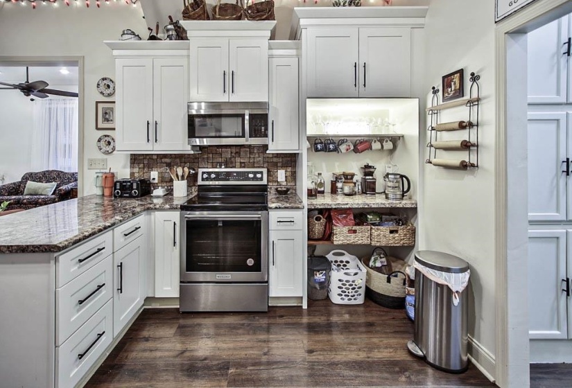 Kitchen featuring white cabinetry, appliances with stainless steel finishes, backsplash, and kitchen peninsula