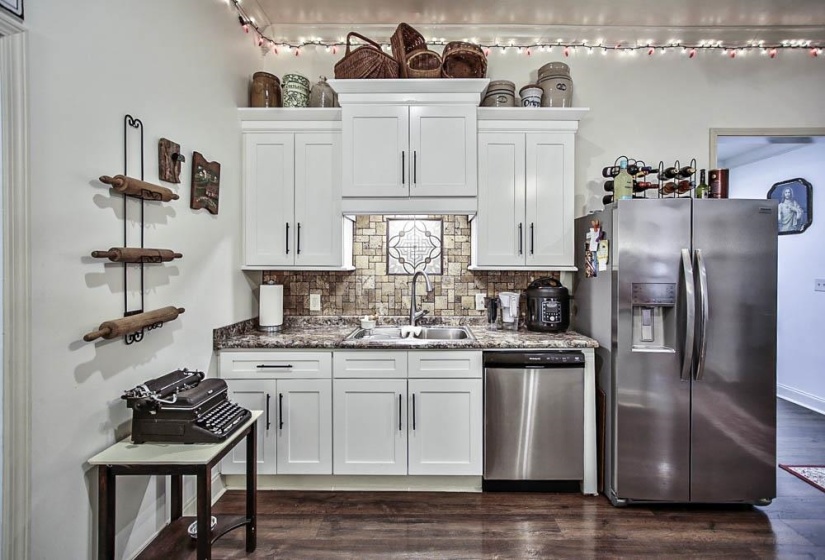 Kitchen with white cabinetry, sink, backsplash, and stainless steel appliances