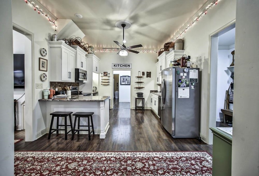 Kitchen featuring appliances with stainless steel finishes, dark stone countertops, white cabinets, decorative backsplash, and kitchen peninsula