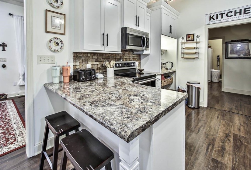 Kitchen featuring a breakfast bar, stainless steel appliances, light stone countertops, and white cabinets