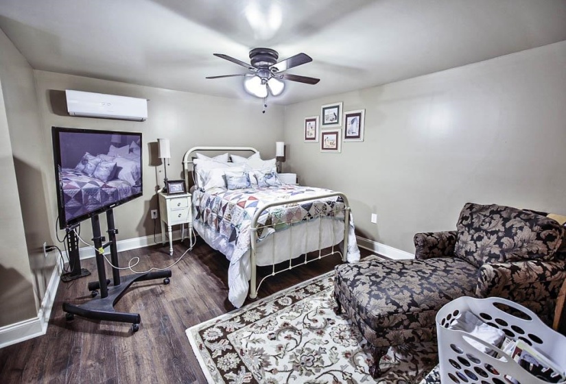 Bedroom featuring ceiling fan, a wall mounted air conditioner, and dark hardwood / wood-style floors