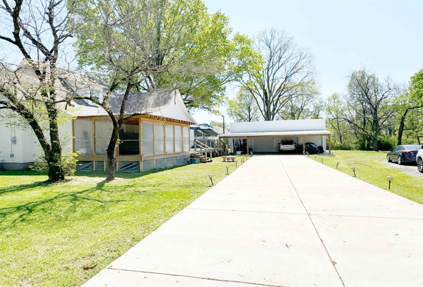 View of front facade with a carport, driveway, a front yard, and an outdoor structure