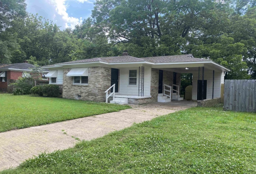 View of front facade with a carport and a front lawn