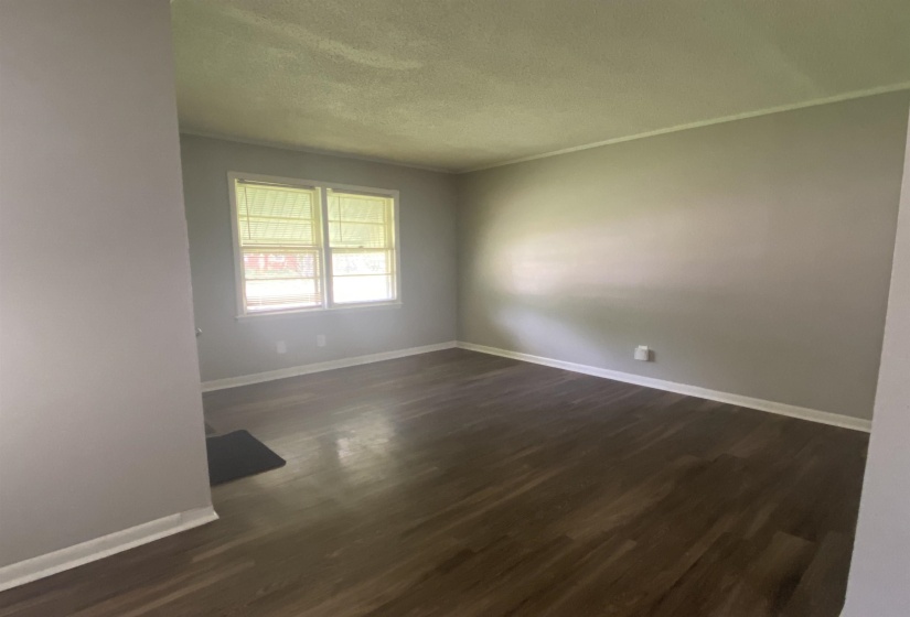 Empty room with dark hardwood / wood-style floors and a textured ceiling