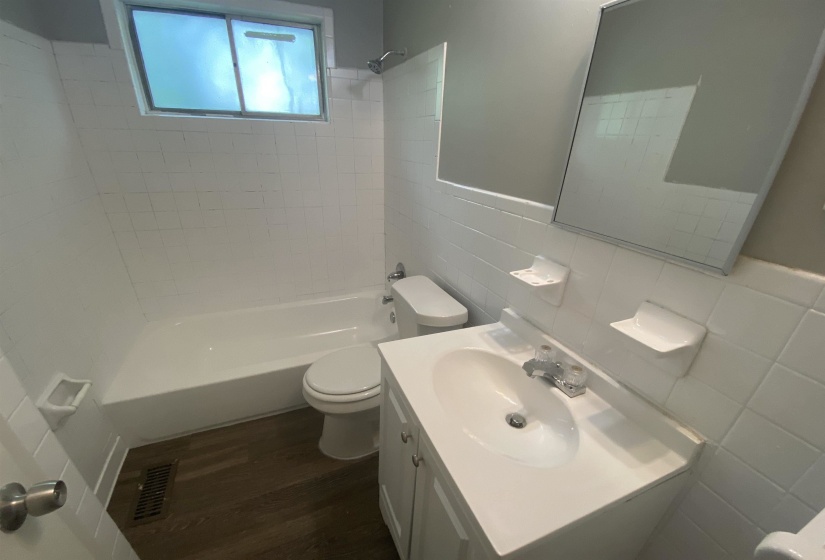 Full bathroom featuring toilet, tile walls, vanity, tiled shower / bath combo, and hardwood / wood-style flooring