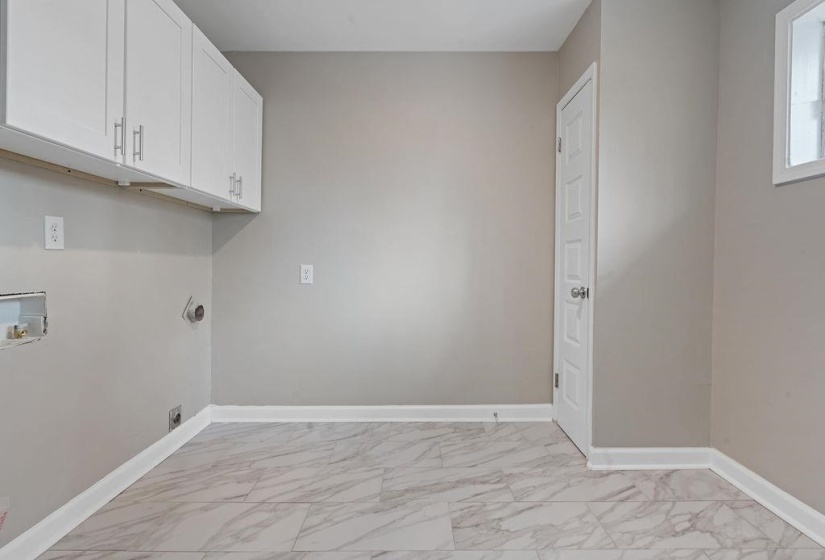 Clothes washing area with washer hookup and cabinets