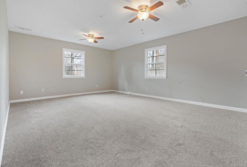 Carpeted empty room with two ceiling fans and a healthy amount of sunlight