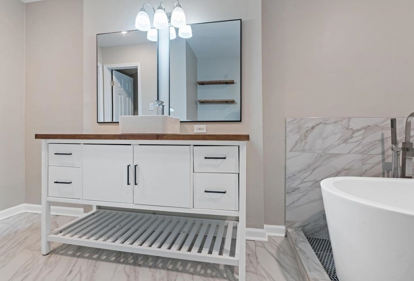 Bathroom with vanity, a tub, and tile walls